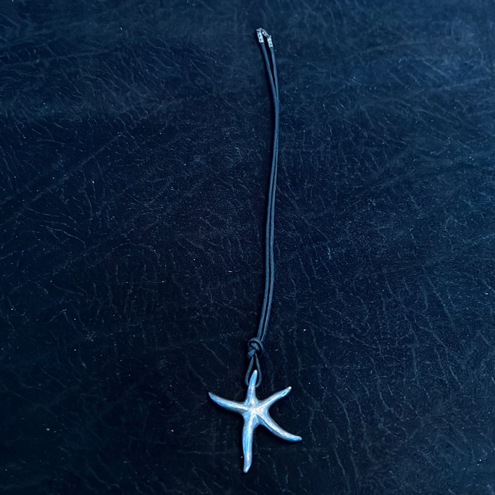 Sterling silver star pendent on black cord necklace.